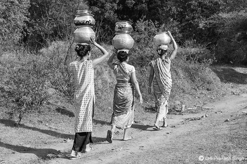 Hauling drinking water from a distant source across a forested path in Khunti district, Jharkhand, India